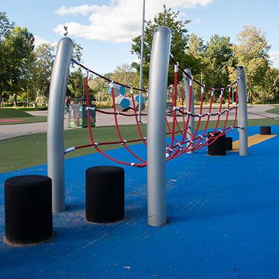 Ein Hindernisparcours mit balancierenden Trittsteinen und einer wackeligen Brücke auf einem Spielplatz.